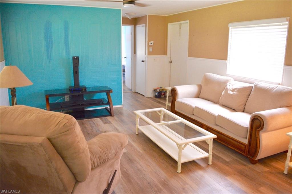 Open concept living area featuring wood-finish flooring, a ceiling fan, and a window with blinds