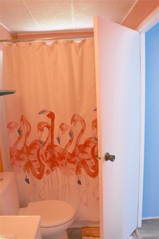 Bathroom featuring a white toilet, light-colored walls, and a textured ceiling