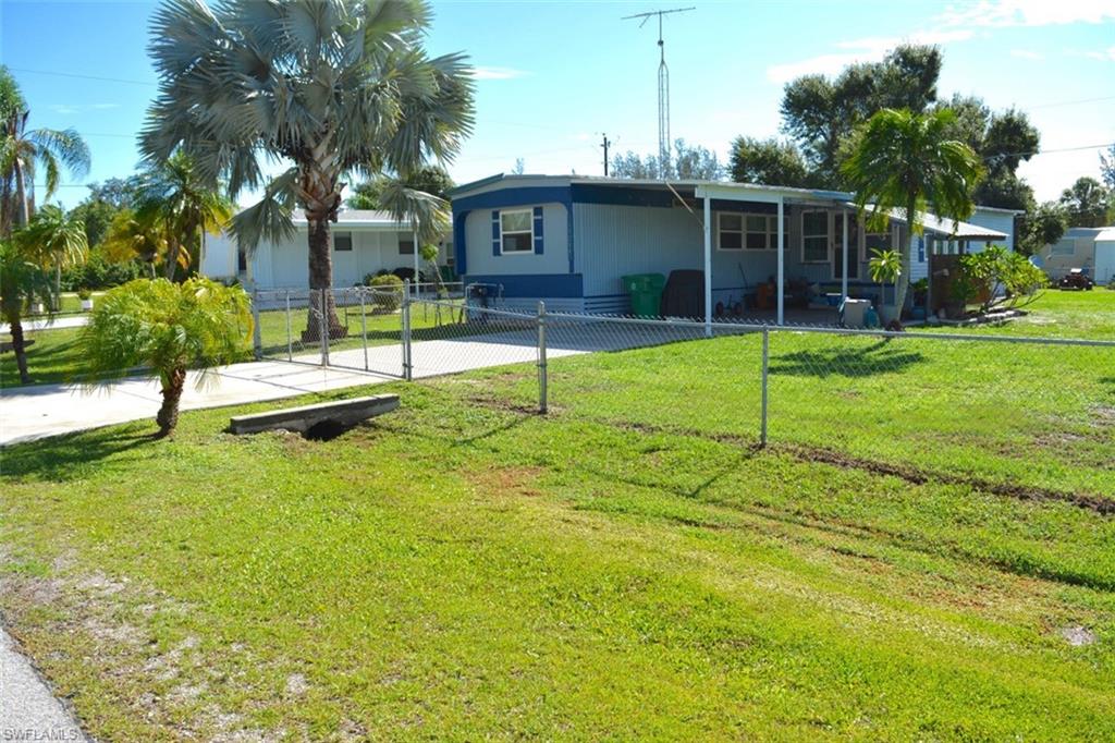 Chain link fenced perimeter with a paved driveway and mature palm trees