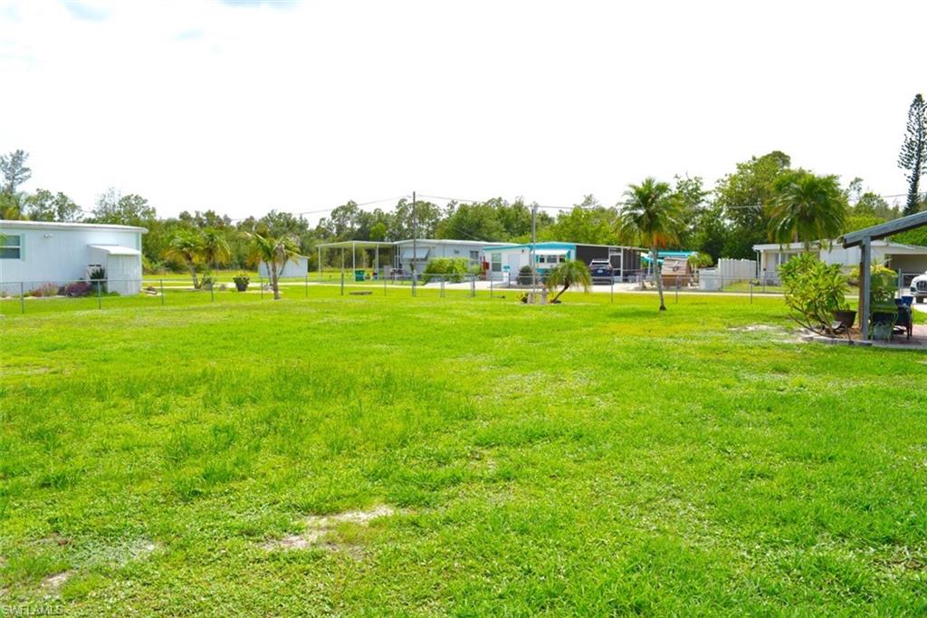 Expansive green lawn with visible perimeter fencing and mature palm trees