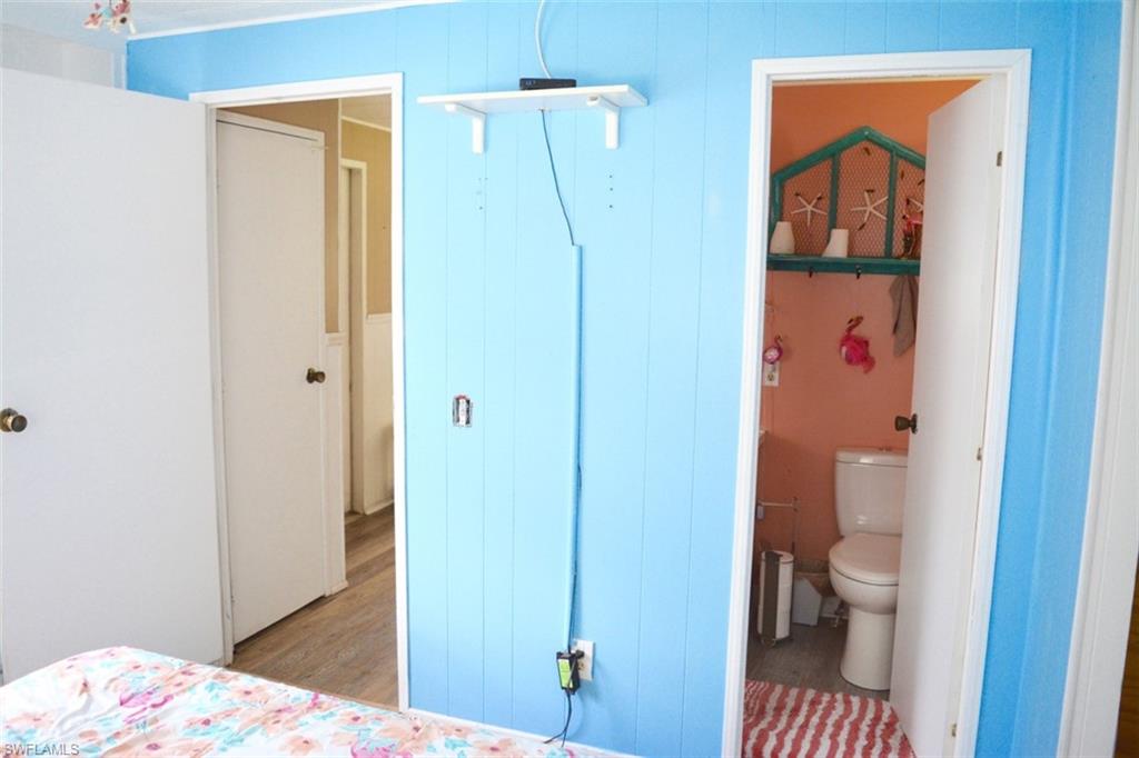 Powder room featuring a white toilet, peach-toned walls, and wood-finish flooring