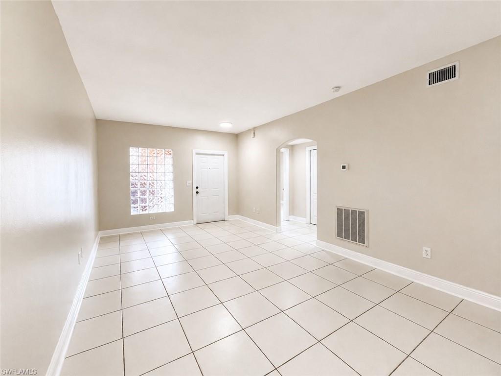 Spacious room featuring light-toned tile flooring, neutral wall paint, and white baseboards