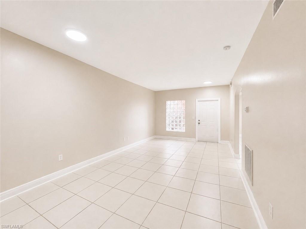 Spacious room featuring tile flooring, neutral wall tones, recessed lighting, and a glass block window for filtered natural light