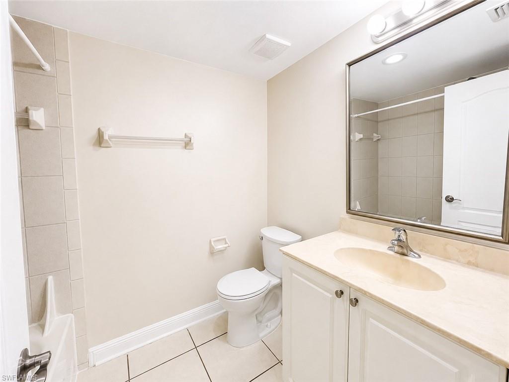 Bathroom featuring a vanity with a light-toned countertop and integrated sink, a rectangular framed mirror, and a toilet
