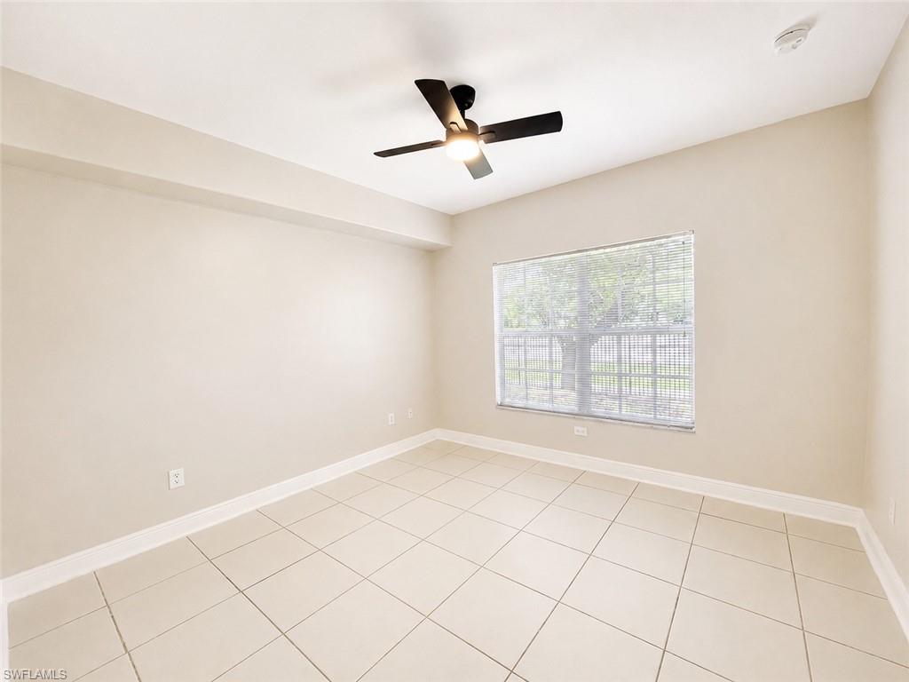 Spacious room featuring neutral-toned walls, diagonal tile flooring, and a ceiling fan with integrated lighting