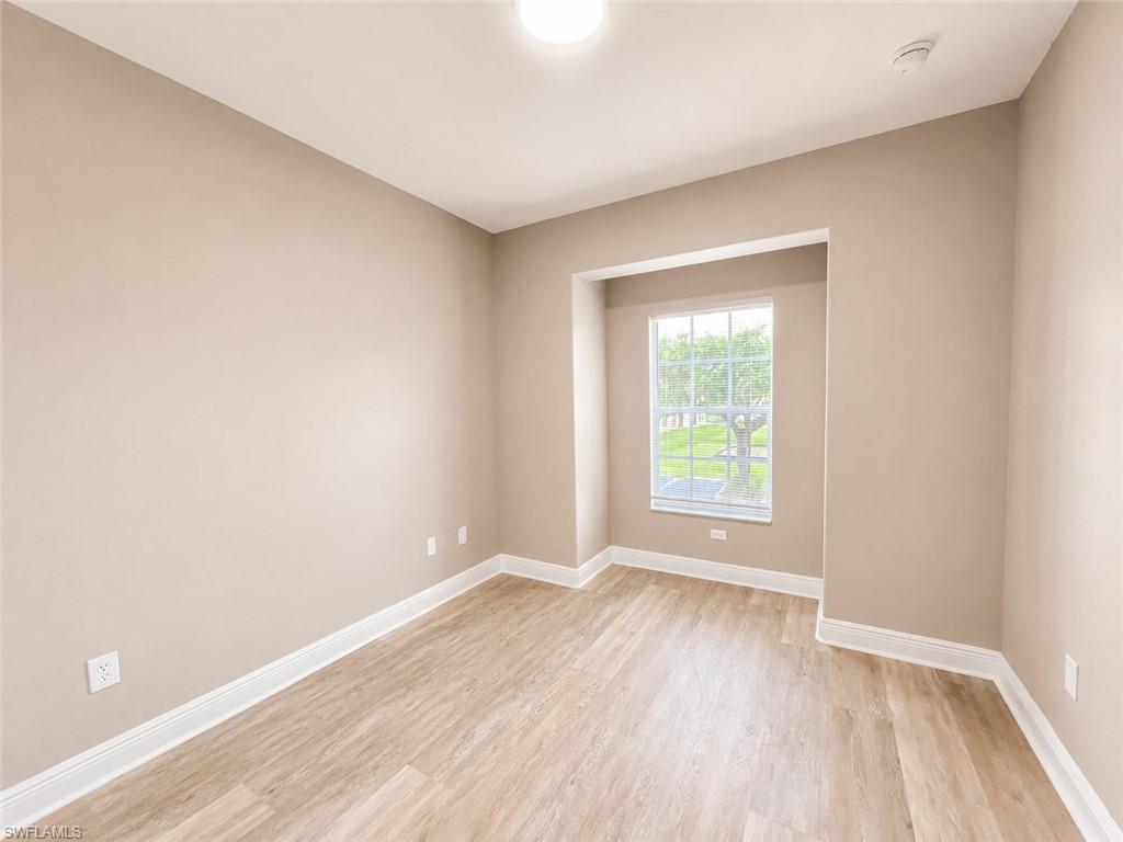 Neutral-toned room featuring light wood-finish flooring and white baseboards