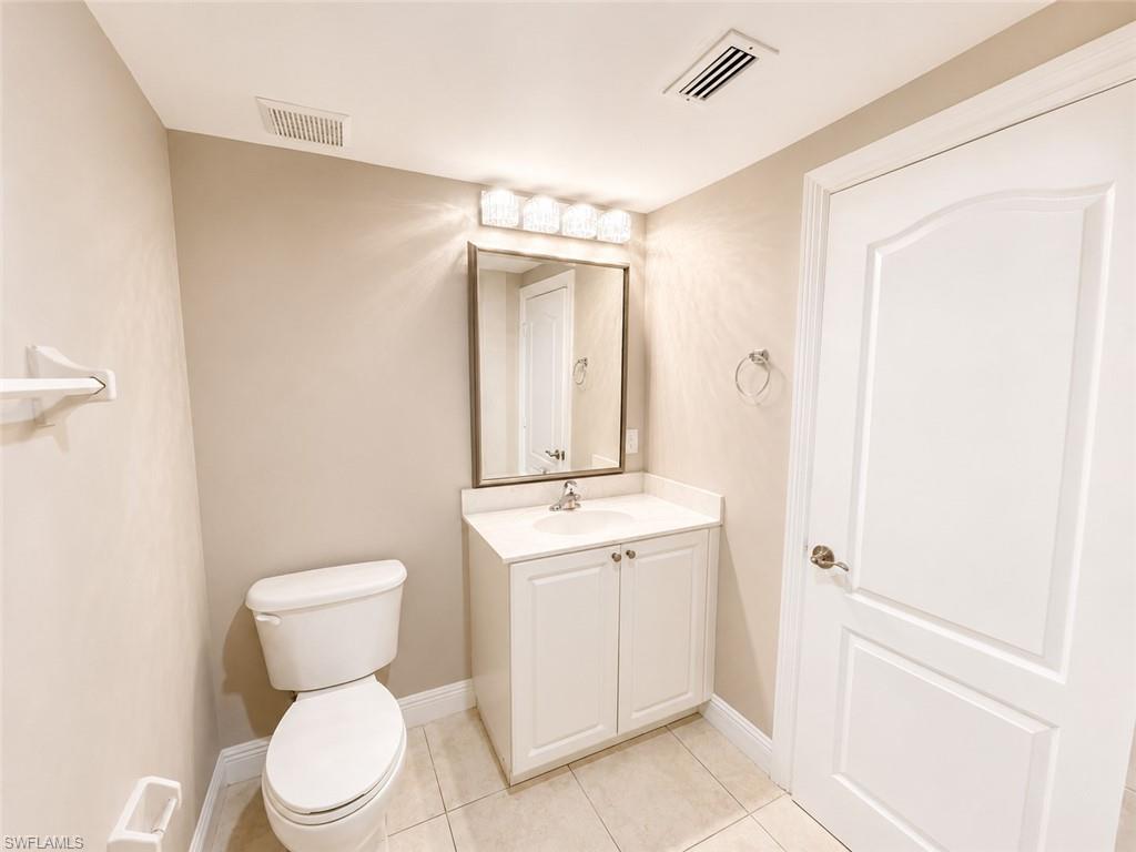 Bathroom featuring a white vanity with an integrated sink, polished chrome hardware, a framed mirror, and tiled flooring