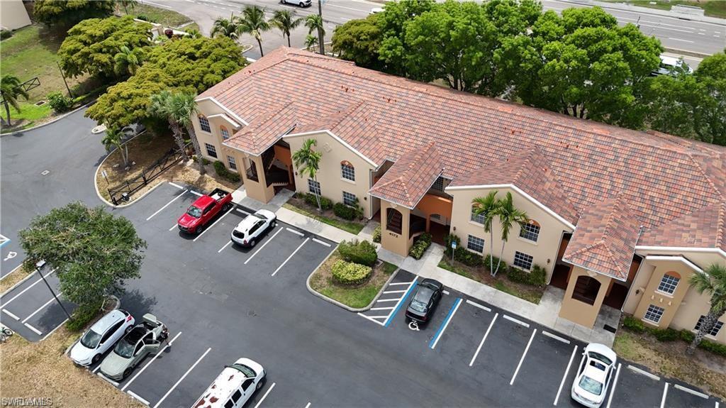Multi-unit property featuring a terra cotta tile roof, stucco exterior, multiple entranceways, and ample paved parking