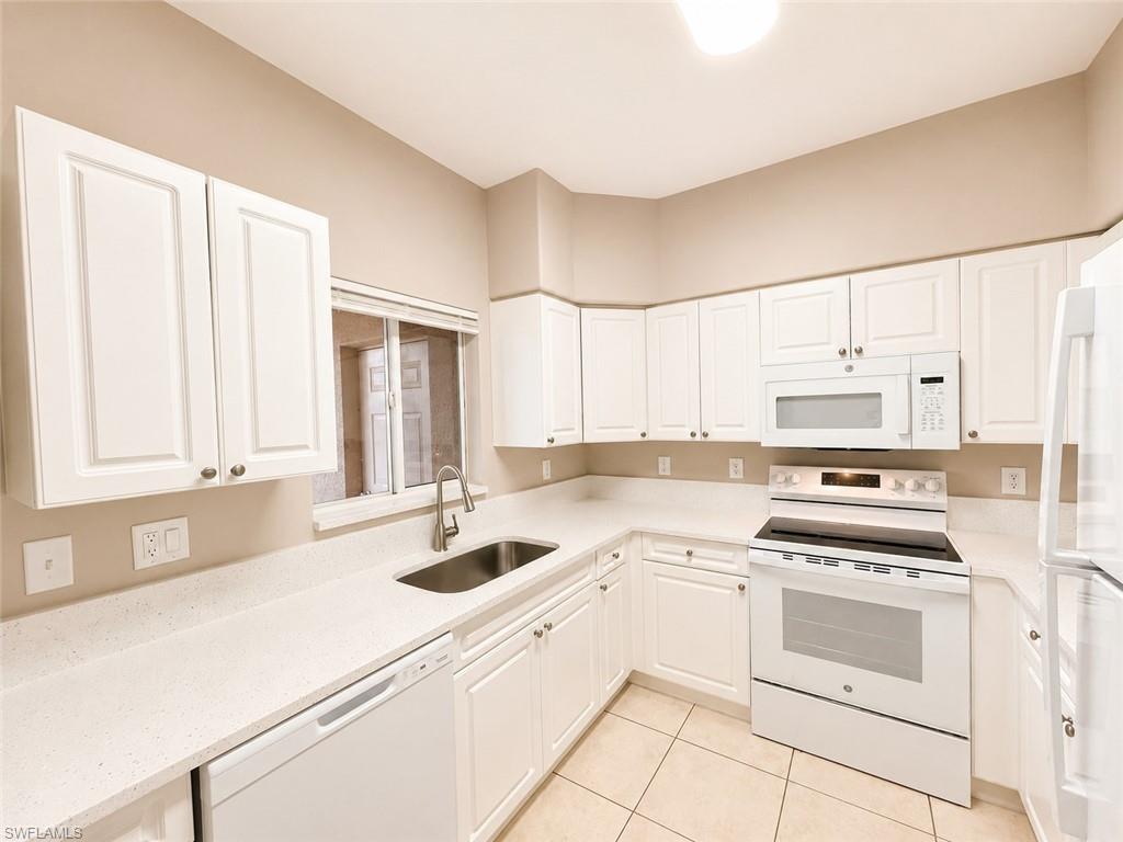 Kitchen featuring white cabinetry, white appliances, light-toned countertops, and tile flooring