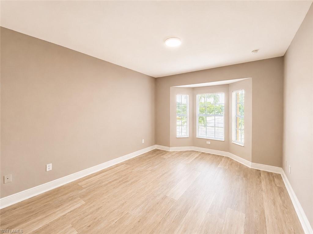 Room with bay window featuring three individual windowpanes, wood-finish flooring, and light neutral wall tones