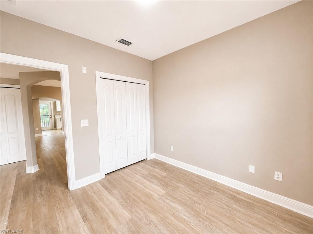 Interior room featuring wood-finish flooring, neutral wall tones, white trim, and a double bi-fold closet