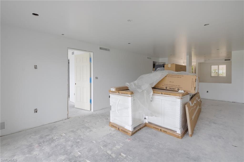Living area with new quality Kitchen cabinets ready for installation.  The door on the left leads to the Primary Bedroom