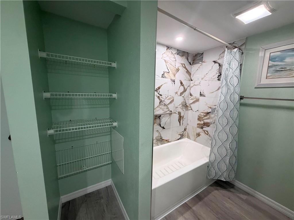 Bathroom featuring a tub/shower combination with large format marble-look tile surround and a recessed niche