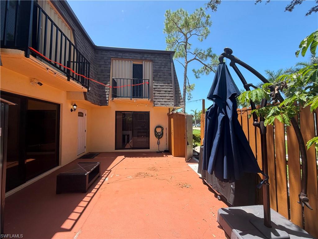 Spacious outdoor patio area featuring a red-hued concrete surface, wood-paneled fencing, and a two-story exterior with balconies