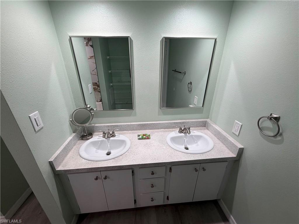 Double vanity with white cabinetry, light speckled countertop, and two framed mirrors