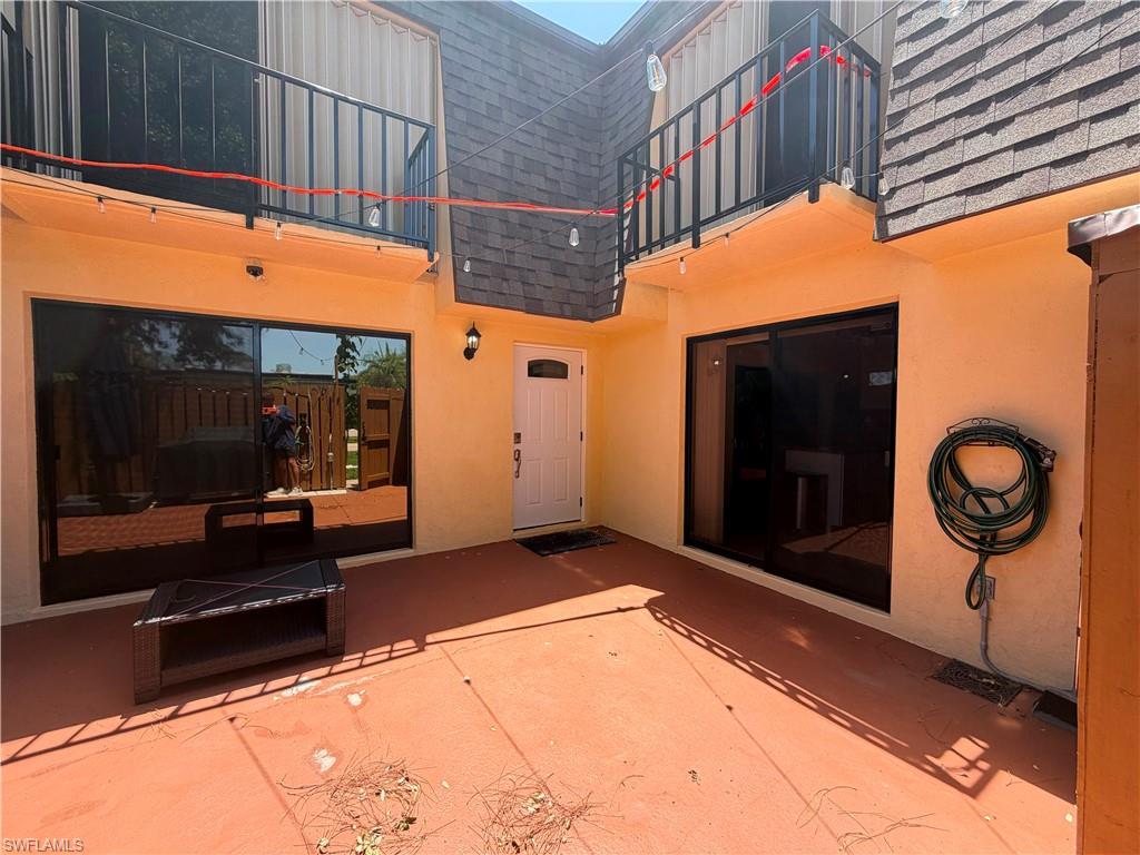 Exterior patio featuring an orange-toned concrete surface, light yellow stucco walls, and a white entry door