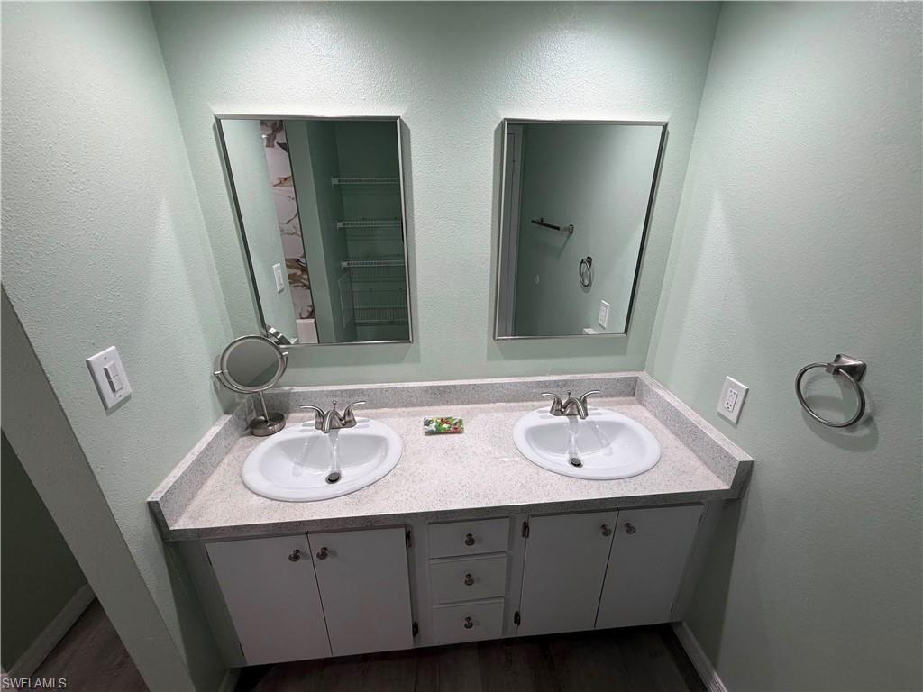 Double vanity with white cabinetry, light speckled countertop, dual undermount sinks, and individual framed mirrors