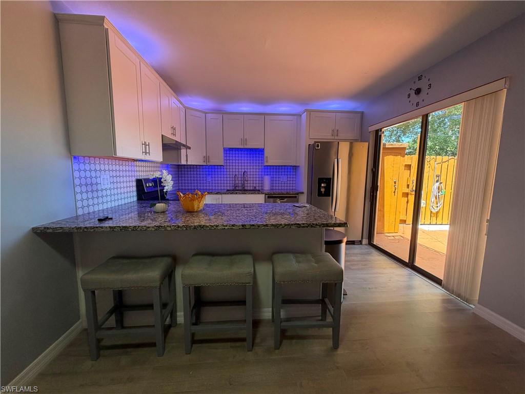 Kitchen featuring white cabinetry, granite countertops, and a full tile backsplash