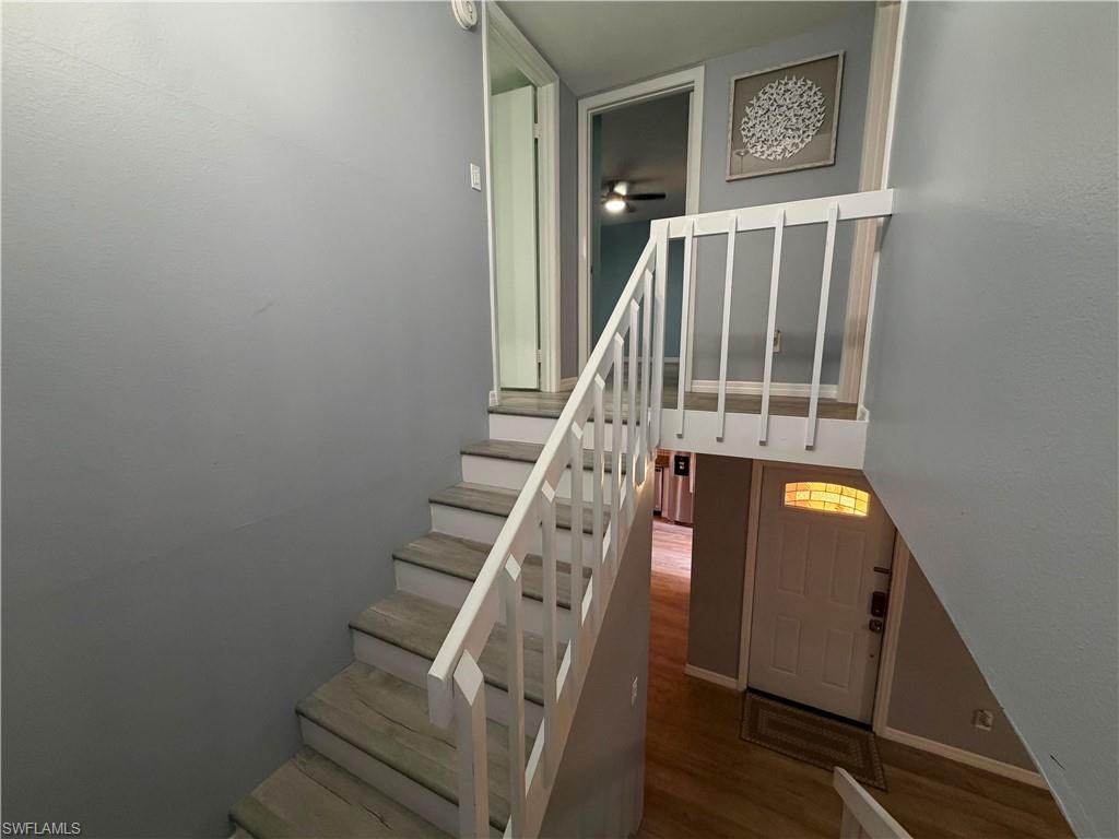 Staircase featuring wood-finish flooring treads and risers with white painted railings