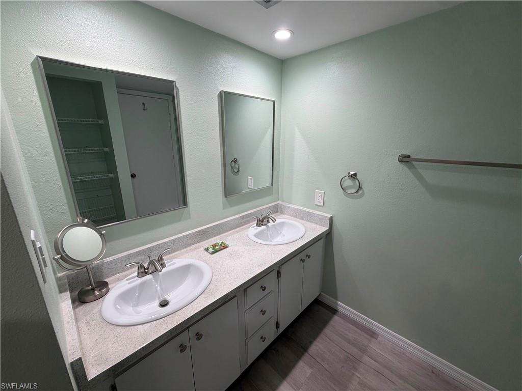 Bathroom featuring a dual vanity with white oval sinks, brushed nickel faucets, and a speckled countertop