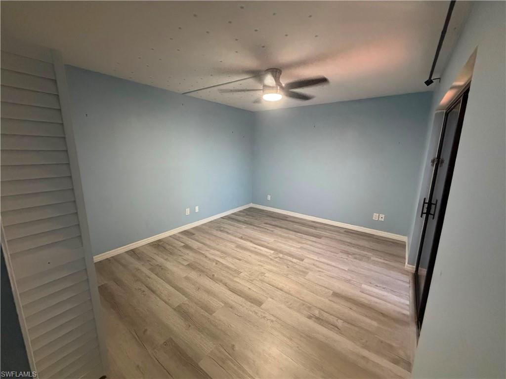 Spacious room featuring light blue walls, wood-finish flooring, and white baseboards