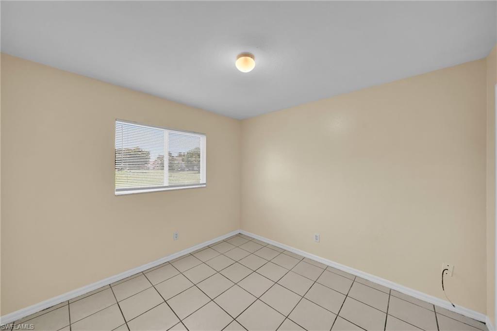 Room featuring ceramic tile flooring, a single window with horizontal blinds, and neutral-toned wall paint