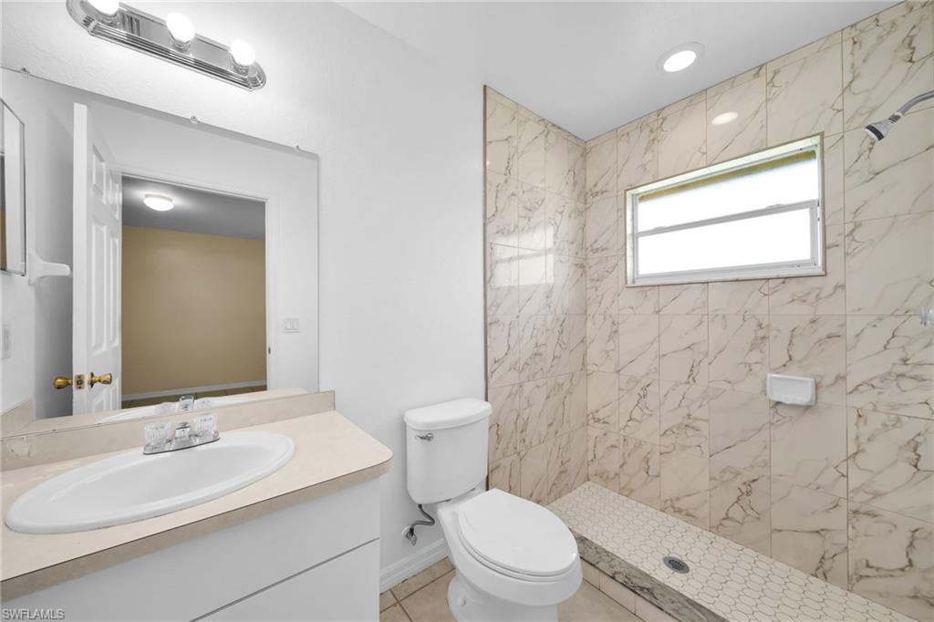 Bathroom featuring a walk-in shower with large format marbled tile, a window, and hexagonal floor tile