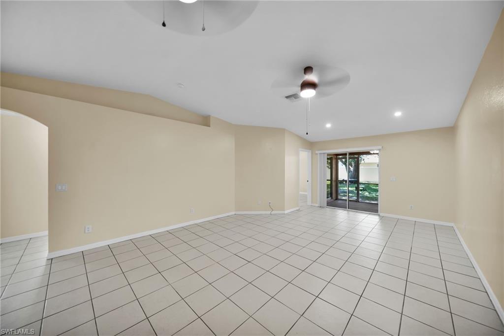 Spacious room featuring neutral-toned walls, square tile flooring, recessed lighting, and a ceiling fan