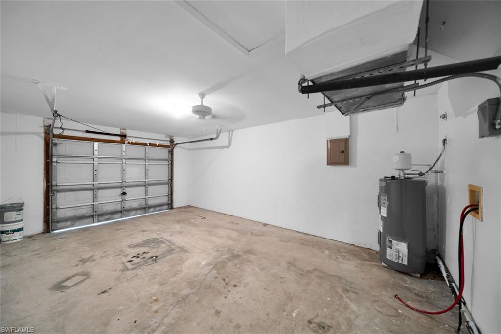 Spacious garage featuring a concrete floor, overhead lighting, and a water heater installation
