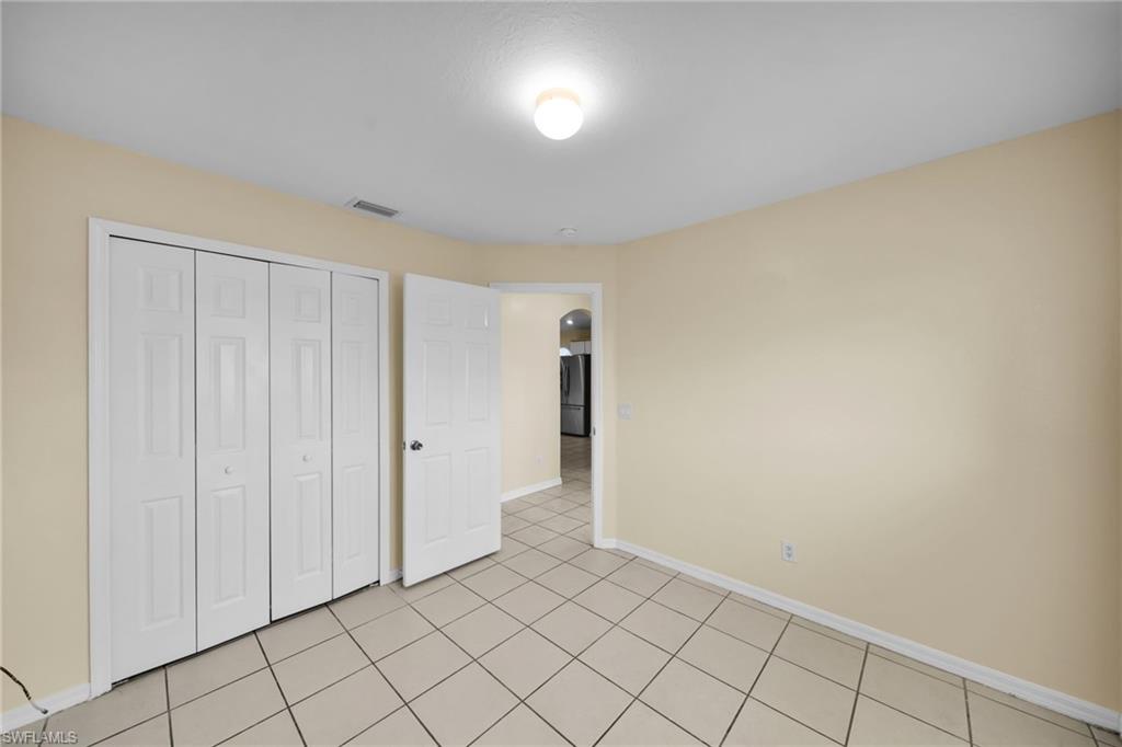 Spacious room featuring neutral-toned walls, white trim, and light-colored square tile flooring