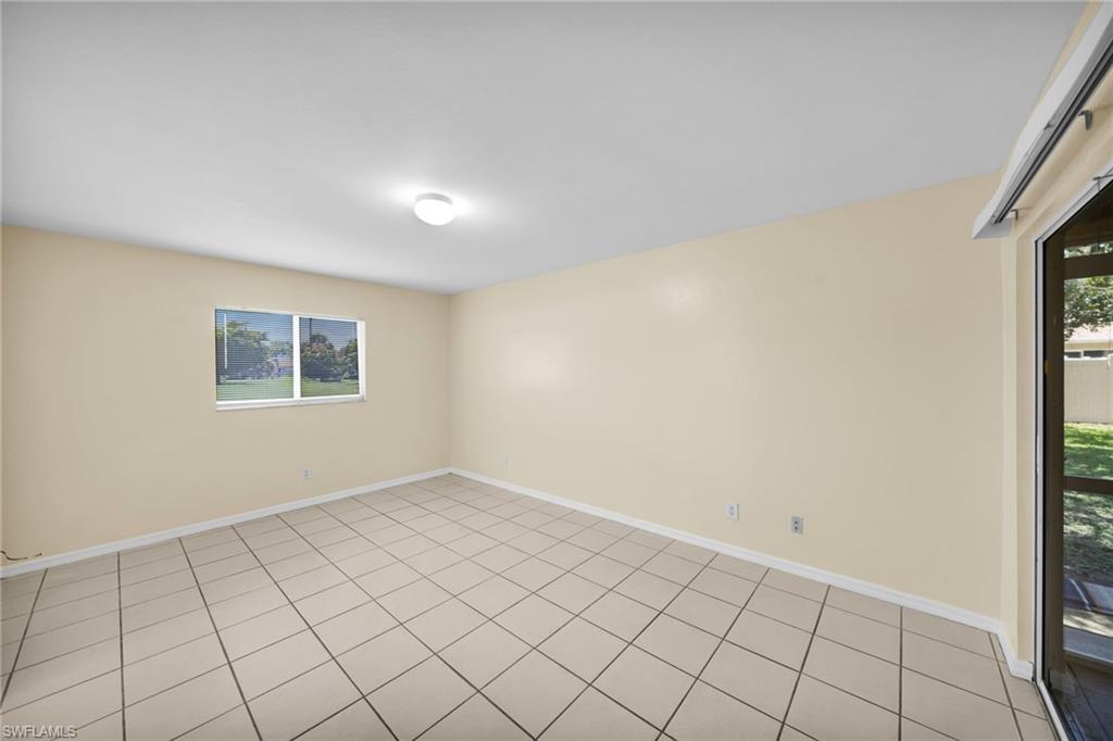 Neutral-toned interior room with tile flooring, a horizontal window offering exterior views, and a ceiling-mounted light fixture