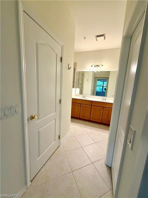 Bathroom featuring tile flooring and a double vanity with wood cabinetry