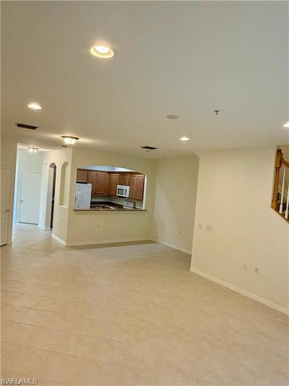 Spacious living area featuring neutral tile flooring, recessed lighting, and a pass-through window to the kitchen