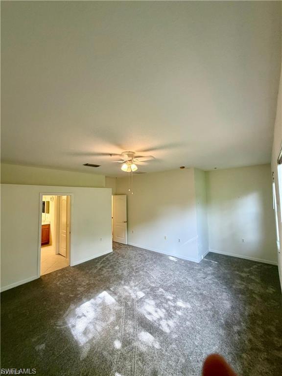 Spacious room featuring neutral carpeting, a ceiling fan with integrated lighting, and white walls