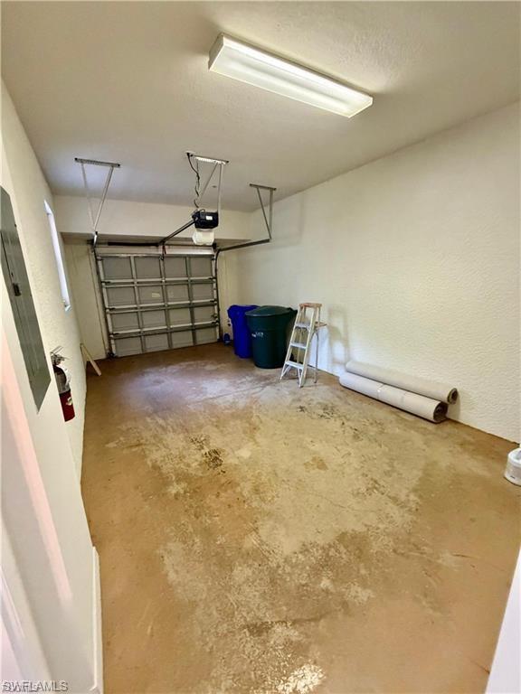 Single-car garage with a roll-up garage door, automatic opener, and overhead fluorescent lighting