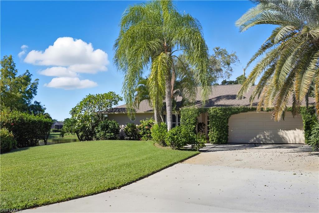 View of front of house with a front yard, concrete driveway, stucco siding, and a garage