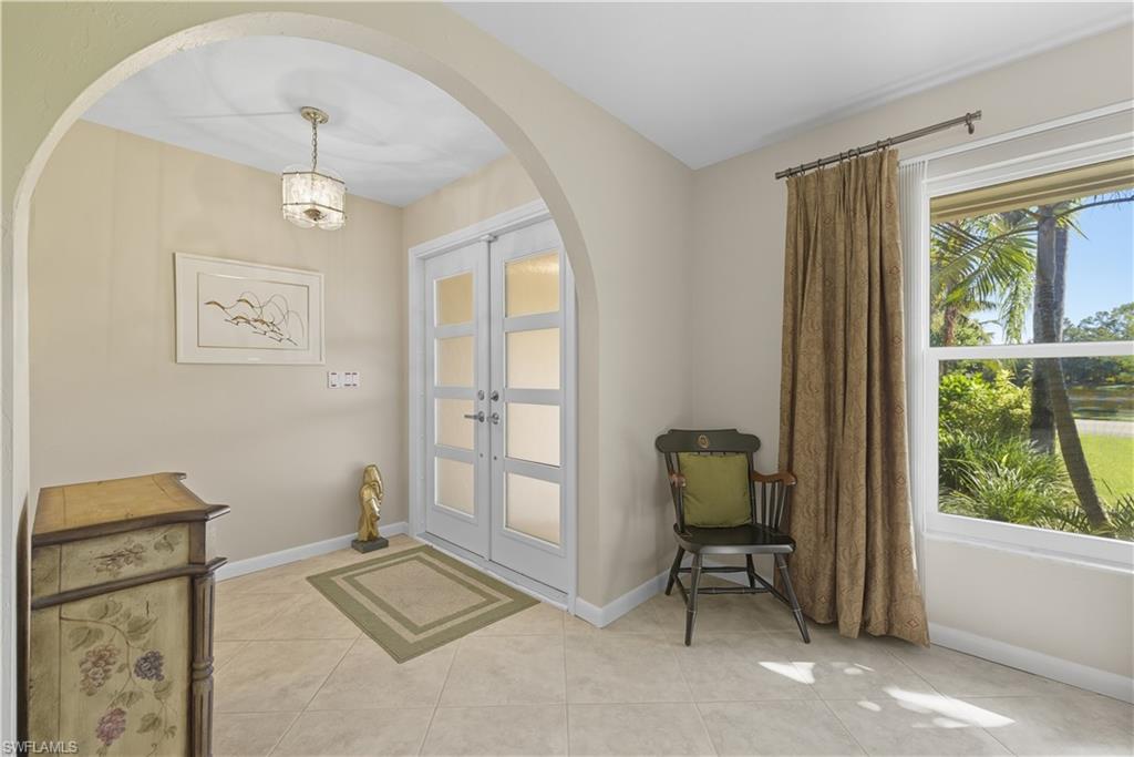 Doorway featuring tile patterned flooring, arched walkways, french doors, and plenty of natural light