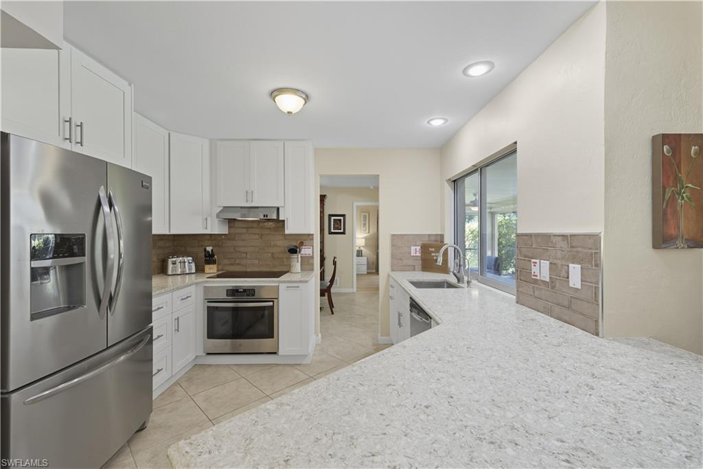 Kitchen featuring appliances with stainless steel finishes, light tile patterned flooring, light stone countertops, white cabinetry, and recessed lighting