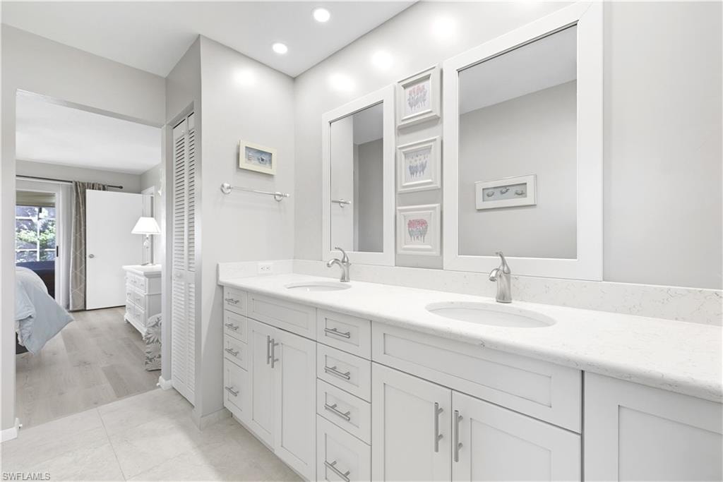 Ensuite bathroom featuring double vanity, light tile patterned floors, a closet, and recessed lighting