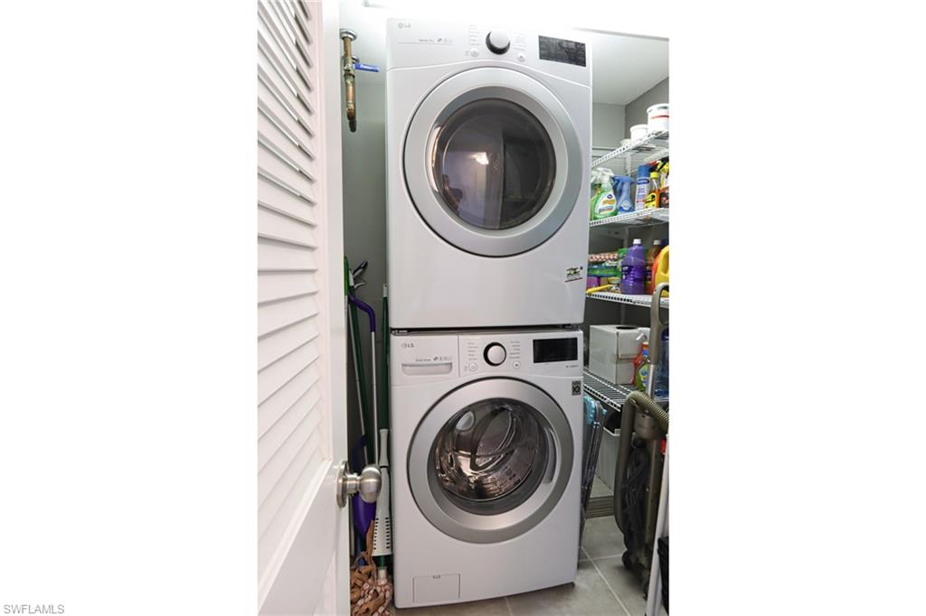 Clothes washing area featuring tile flooring and stacked washer / drying machine