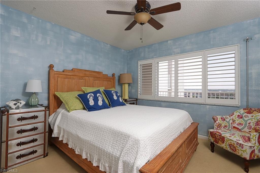 Bedroom with light carpet, ceiling fan, and a textured ceiling