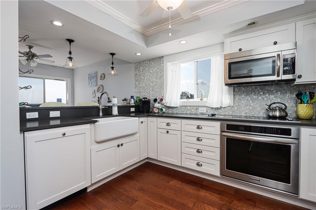 Kitchen with ceiling fan, stainless steel appliances, decorative light fixtures, dark wood-type flooring, and sink