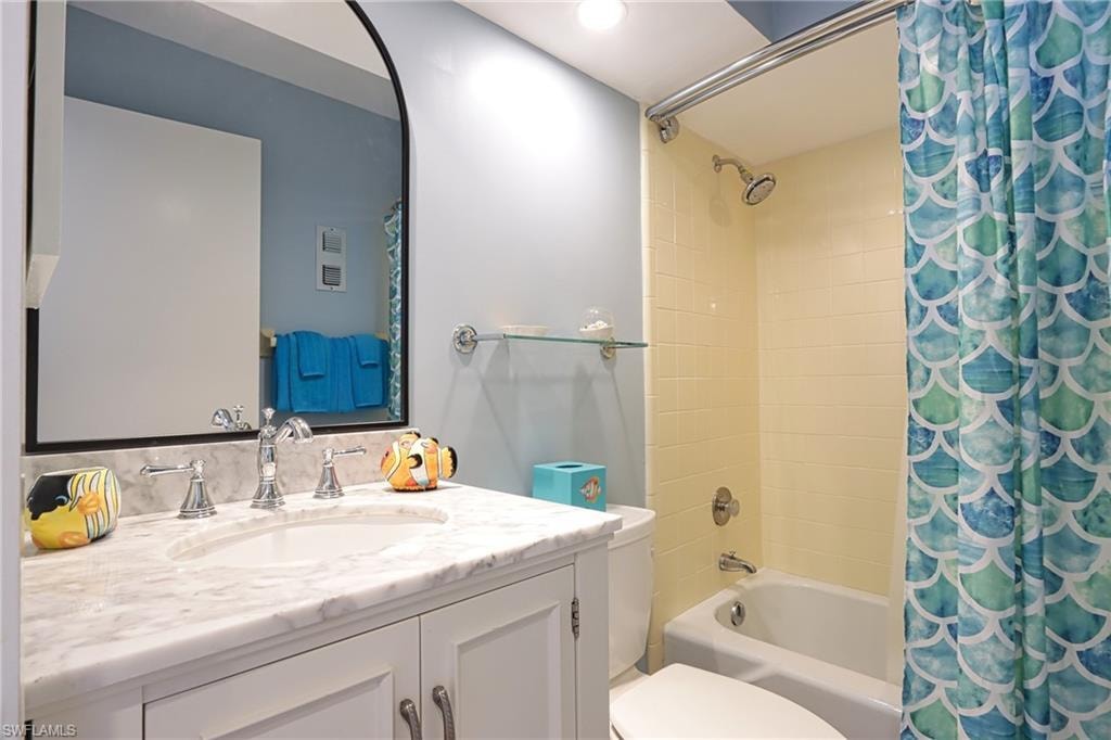 Full bathroom featuring shower / tub combo with curtain, toilet, and vanity
