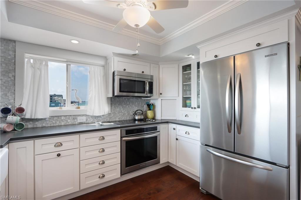 Kitchen featuring white cabinetry, stainless steel appliances, dark hardwood / wood-style floors, tasteful backsplash, and ceiling fan