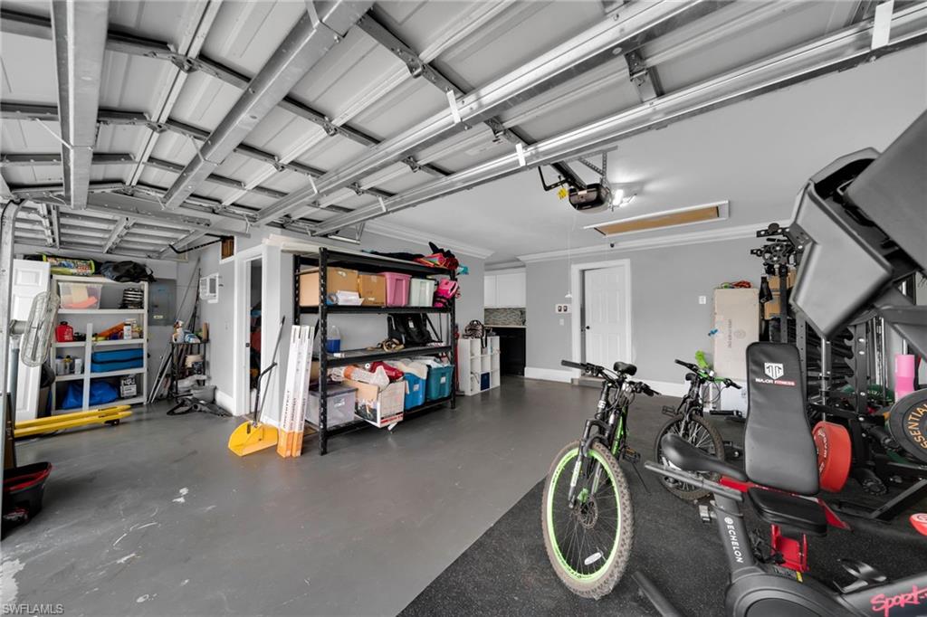 Spacious garage featuring a concrete floor, painted gray walls, white crown molding, and two garage doors with visible tracks and mechanisms