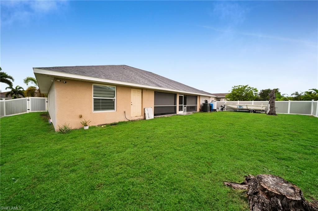 Expansive backyard featuring a manicured lawn, full fencing, screened patio, and a stucco exterior