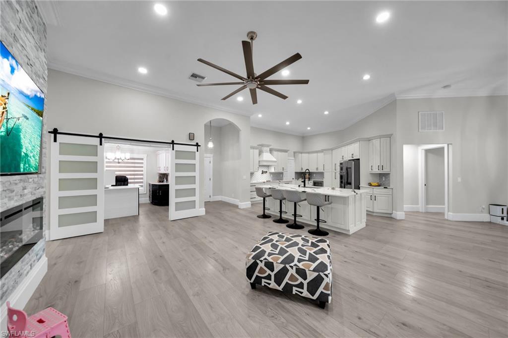 Open-concept living area featuring light wood-finish flooring, recessed lighting, and a contemporary ceiling fan