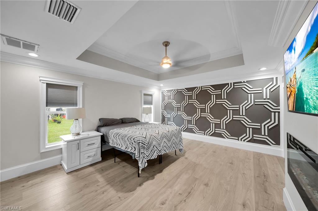 Room featuring a decorative accent wall, tray ceiling, and wood-finish flooring