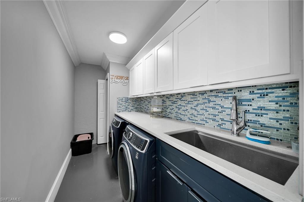 Laundry room featuring white shaker upper cabinetry, dark blue lower cabinetry, and a mosaic tile backsplash