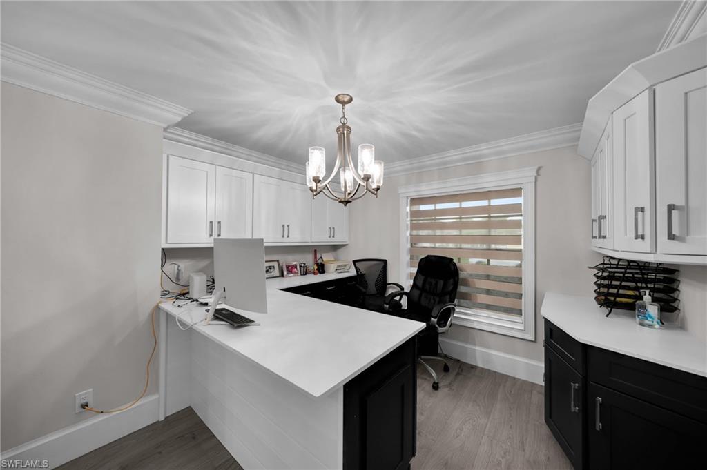 Dedicated office space featuring built-in cabinetry, durable countertops, wood-finish flooring, and crown molding